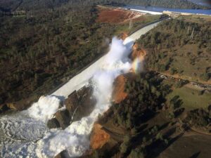 An aerial photo of the damaged spillway of the Oroville Dam and an eroded hillside in 2017. (William Croyle, California Department of Water Resources, Public domain, via Wikimedia Commons)