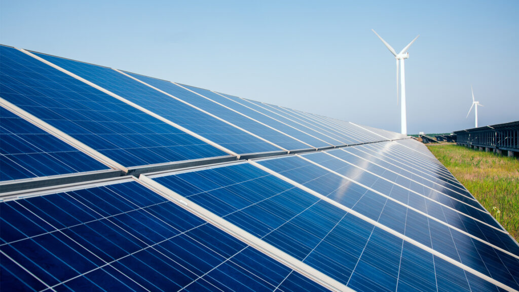 Solar panels with wind turbines in the background (iStock image)