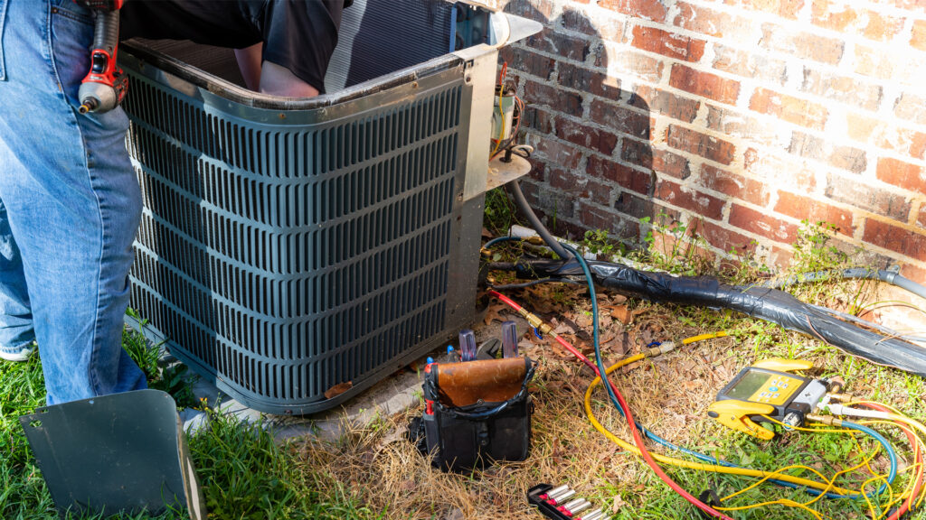 A technician repairs a home air conditioning unit. (iStock image)