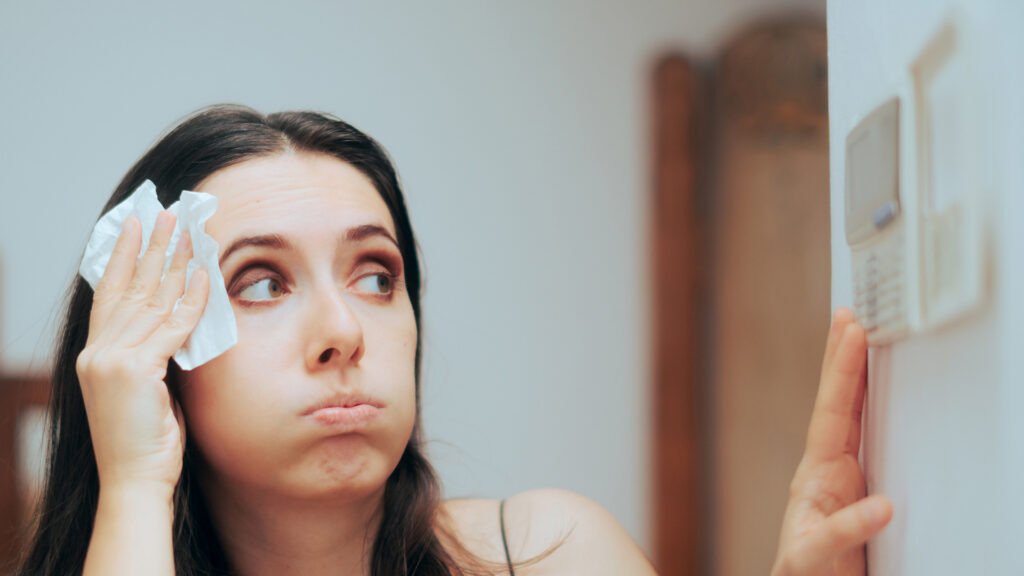 A woman adjusts her thermostat due to the heat (iStock image)