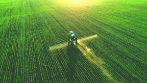 A tractor spreads fertilizer on a field. Fertilizer is a leading source of emissions of nitrous oxide, a planet-warming greenhouse gas. (iStock image)