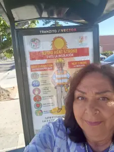 Los Angeles Chief Heat Officer Marta Segura takes a selfie in front of a bus shelter poster on avoiding heat stroke in South Los Angeles. (Courtesy of Marta Segura)