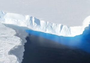 The calving front of Thwaites’ ice shelf. The blue area is light reflecting off ice below the water. (James Yungel/NASA Icebridge)