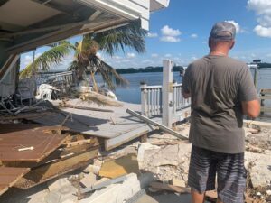 A man looks at the wreckage of a house near water A resident of the Harbor Lights neighborhood, home to Joe Vargas, looks out at the remnants of a house in their community torn apart by Helene. (Ayurella Horn-Muller/Grist)