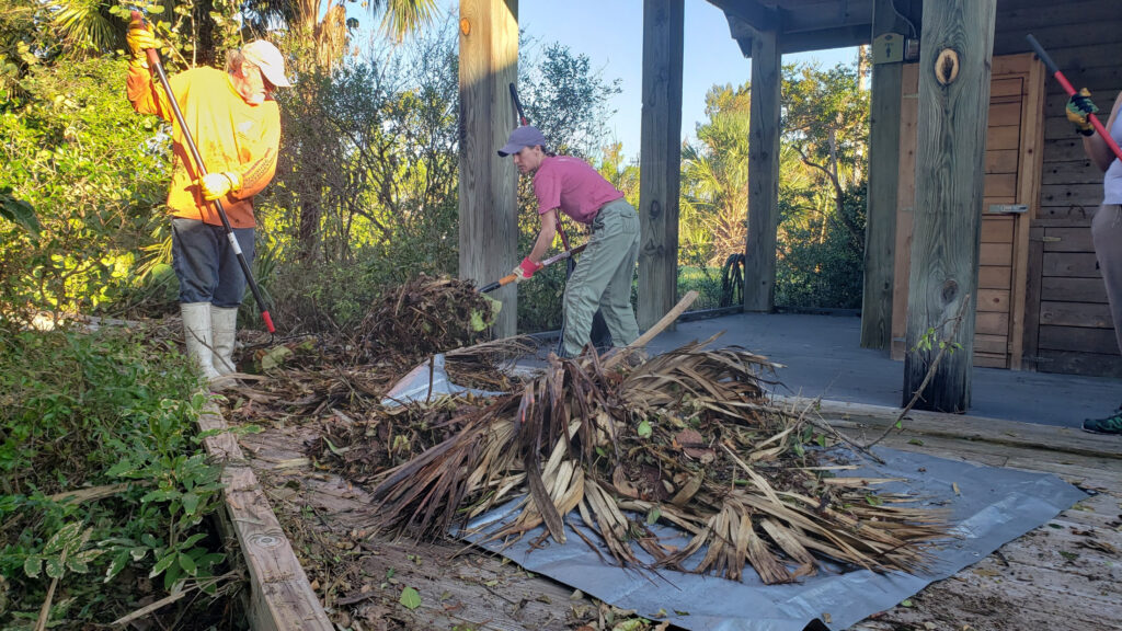 Volunteer Kevin Lollar (left) helped Michelle (center) and others scrub down decking and interior floors to clear away debris and mud. (Florida Museum photo by Annisa Karim)