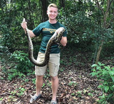 Hunter Howell, then a Ph.D. student in the Conservation Ecology Lab, holds a Burmese python. (University of Miami)